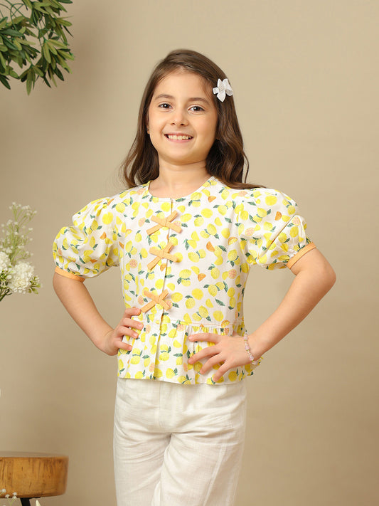 Girls lemon print cotton top with puff sleeves, contrast bow detailing and gathered peplum hem.