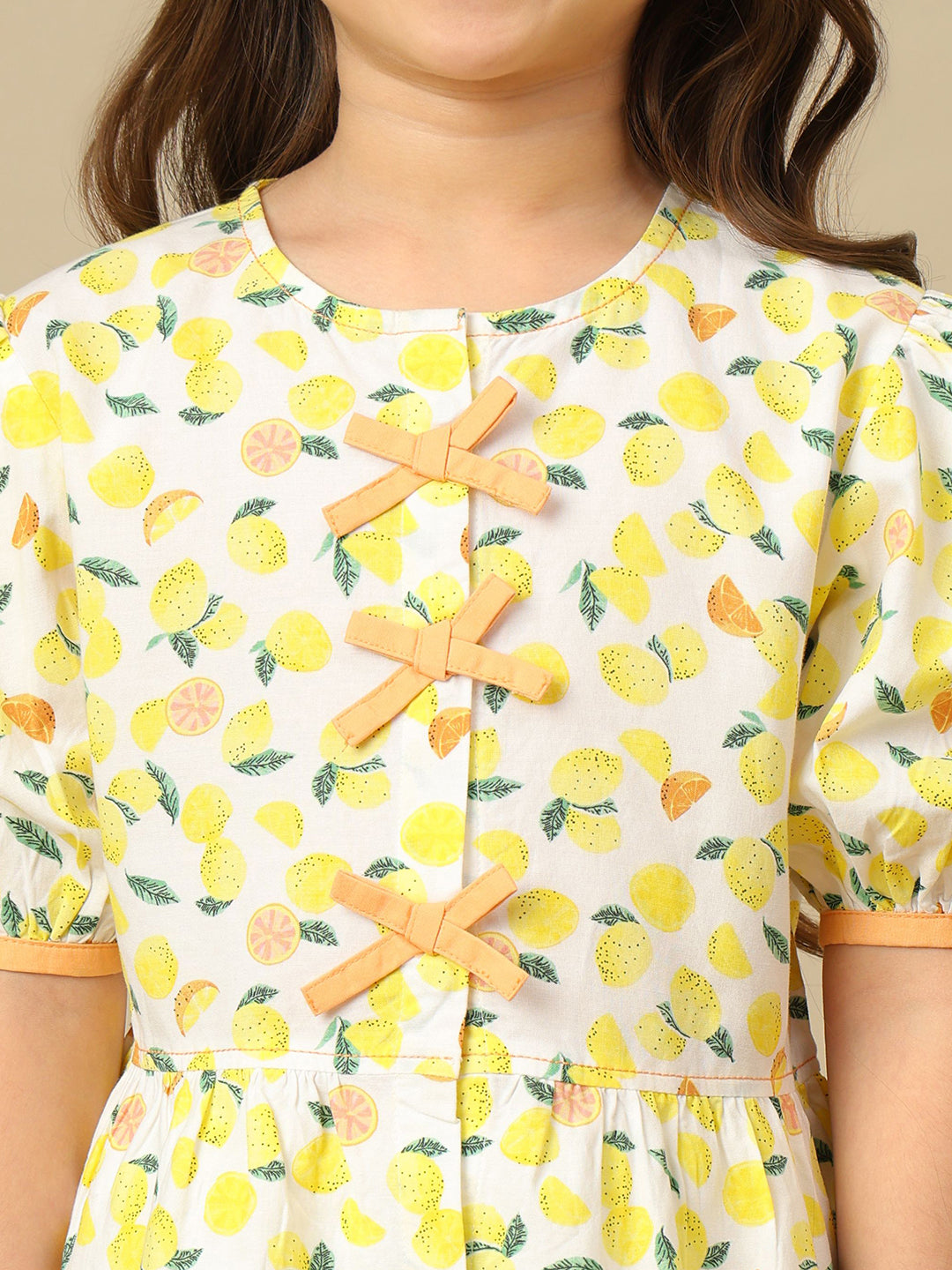 Girls lemon print cotton top with puff sleeves, contrast bow detailing and gathered peplum hem.
