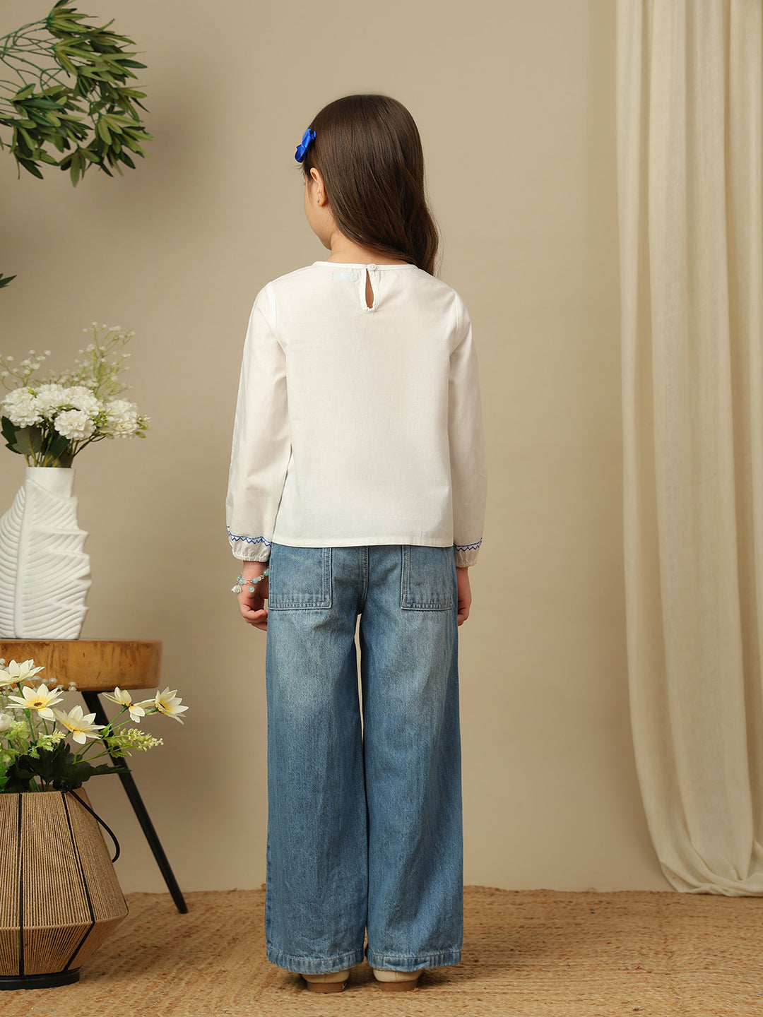 Girls white cotton top with blue embroidery, smocked yoke, round neckline and full sleeves.