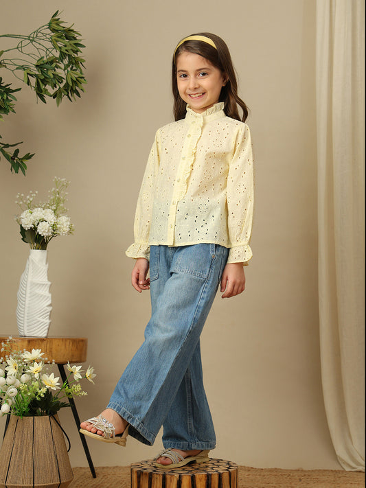 Girls yellow cotton Schiffli shirt with all-over eyelet embroidery, ruffled high neckline, button front and long sleeves.
