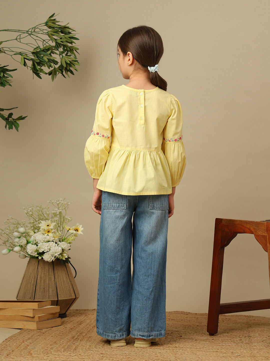 Girls yellow cotton peplum top with multicolour floral embroidery, round neckline and three-quarter balloon sleeves.