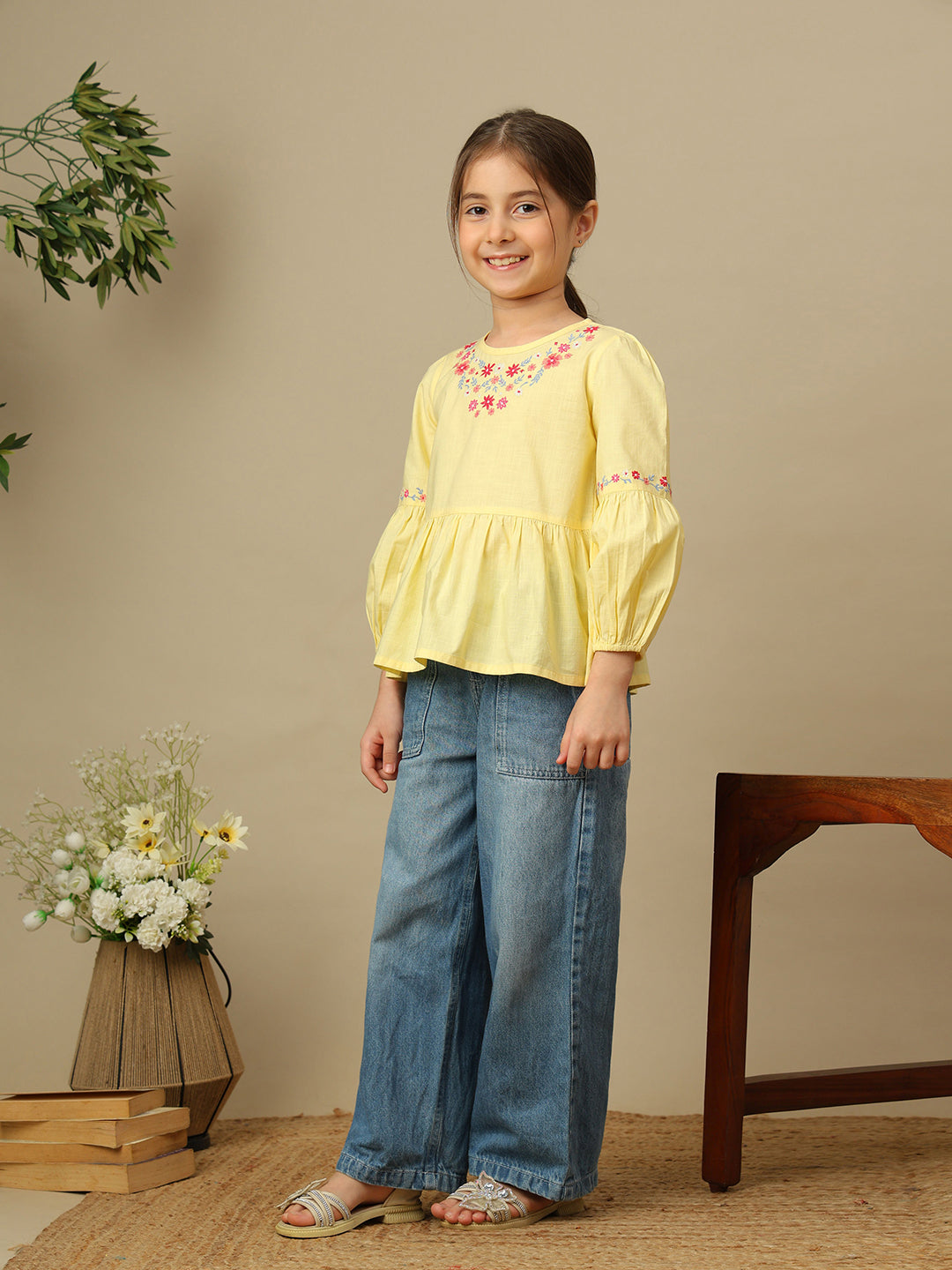 Girls yellow cotton peplum top with multicolour floral embroidery, round neckline and three-quarter balloon sleeves.