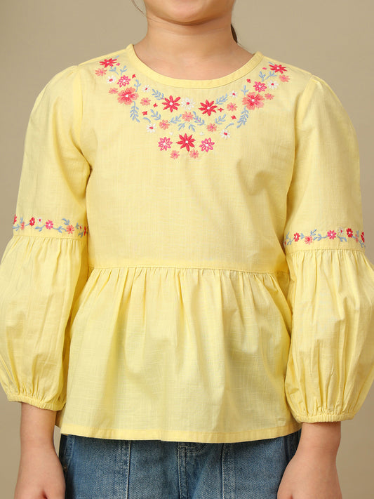 Girls yellow cotton peplum top with multicolour floral embroidery, round neckline and three-quarter balloon sleeves.