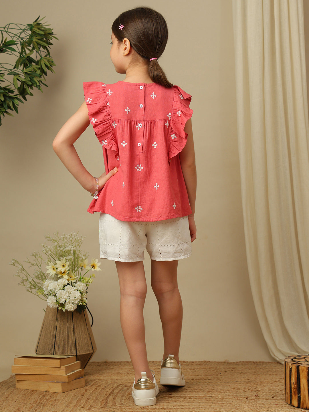 Girls coral cotton top with white floral embroidery, gathered yoke and layered ruffle sleeves.