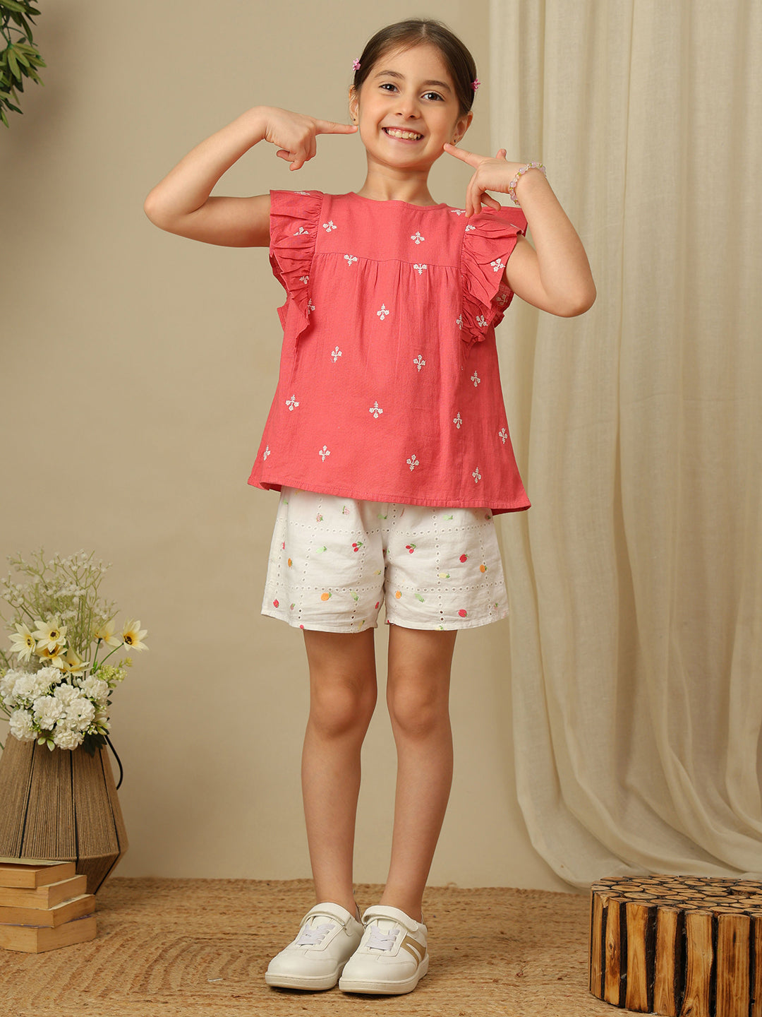 Girls coral cotton top with white floral embroidery, gathered yoke and layered ruffle sleeves.