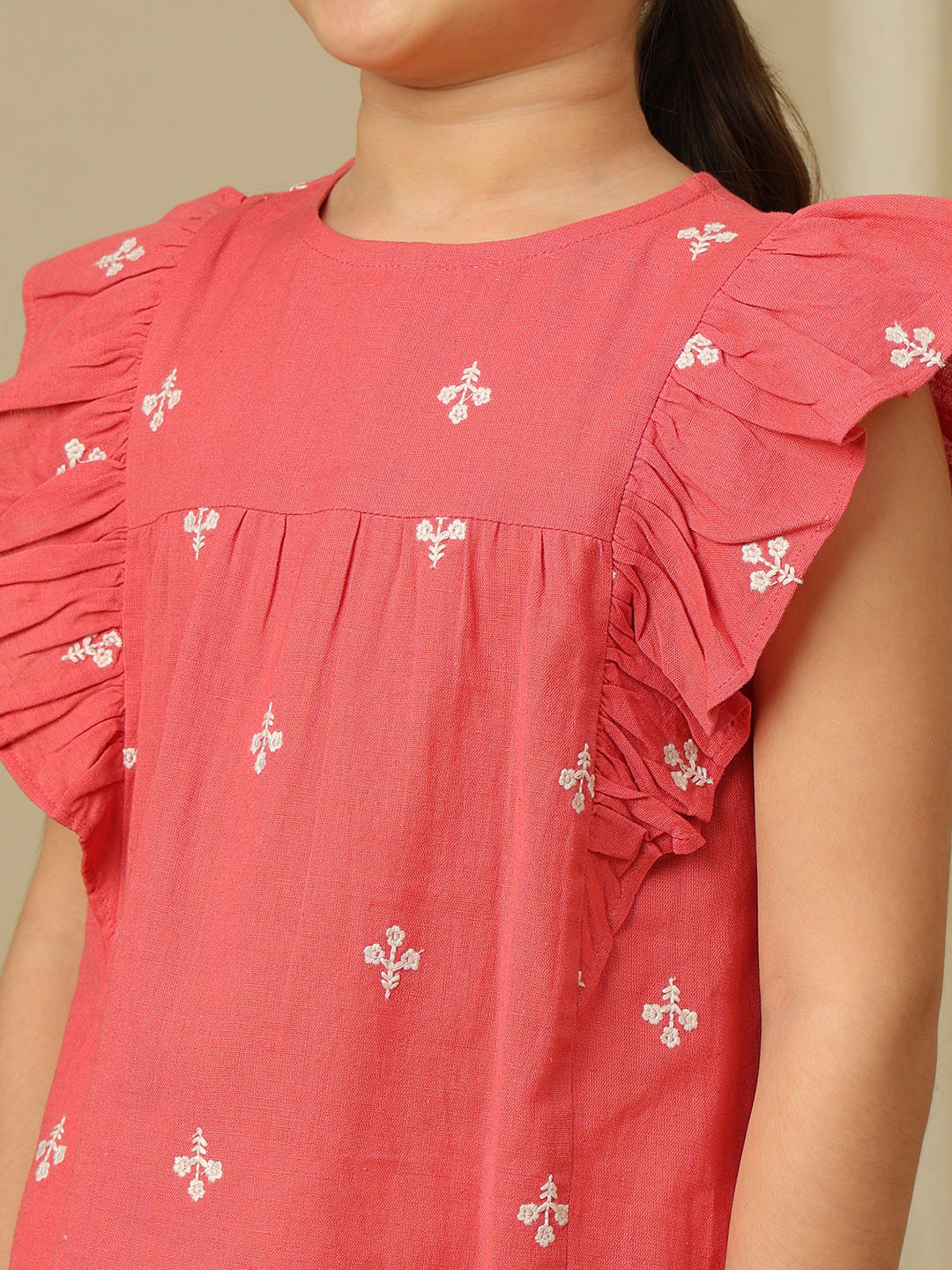 Girls coral cotton top with white floral embroidery, gathered yoke and layered ruffle sleeves.
