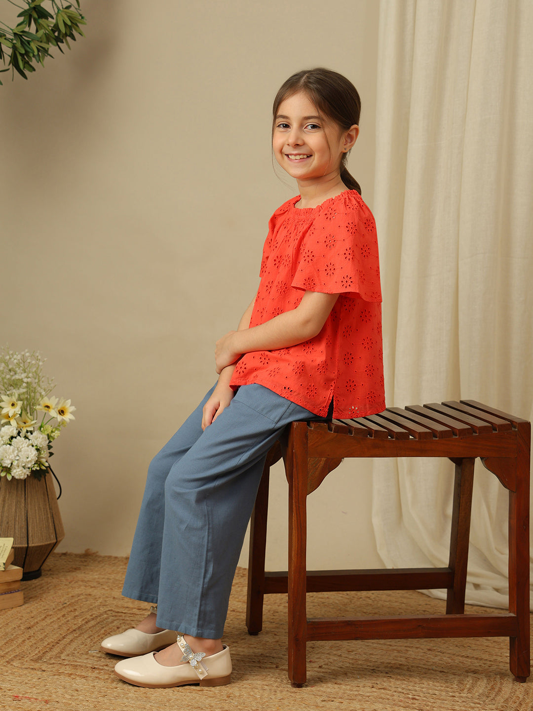 Girls cotton top with floral eyelet embroidery, gathered neckline and flutter sleeves.