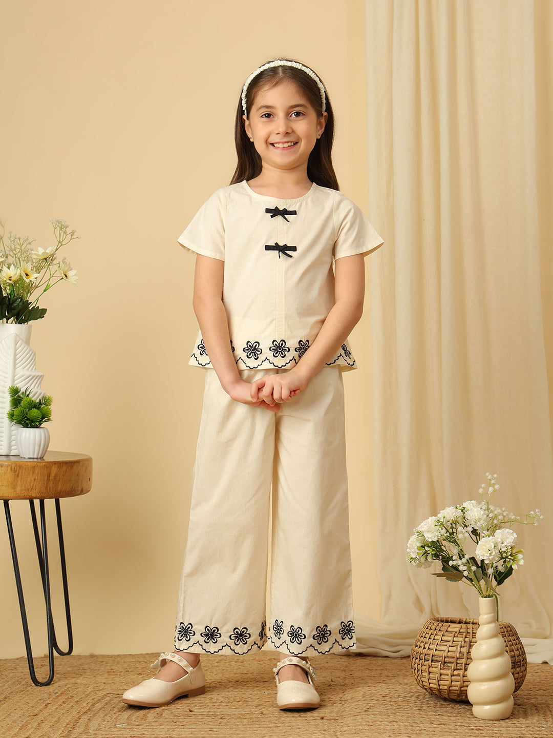 Girls off-white cotton co-ord set with black bow detailing and floral embroidered scalloped hems
