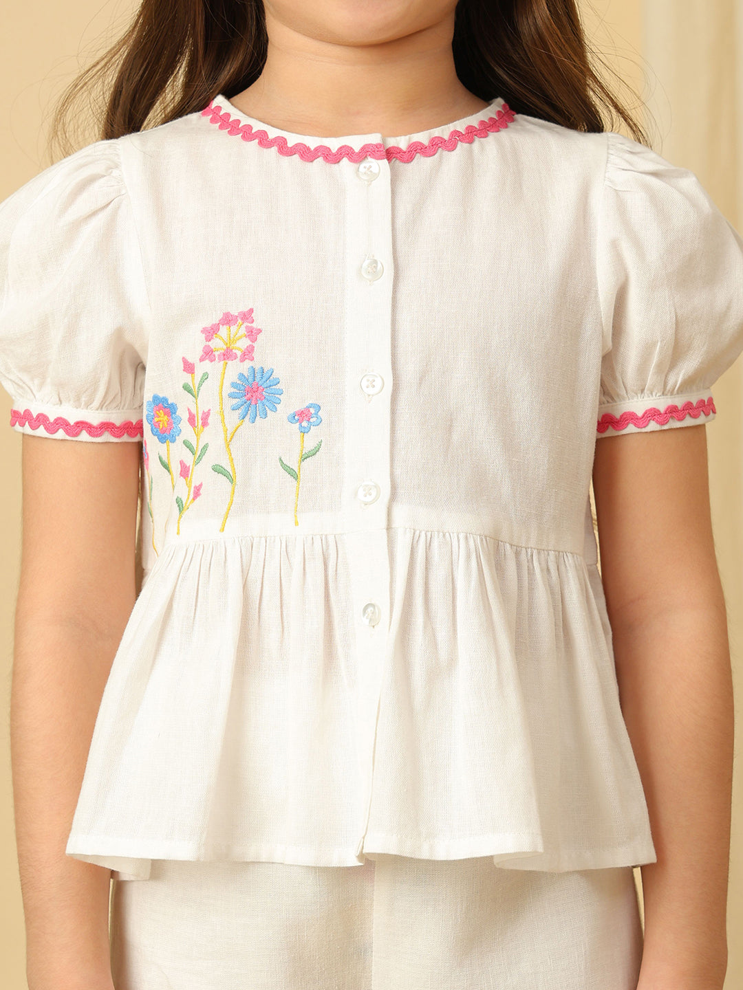 Girls off-white cotton co-ord set with floral embroidered peplum top, puff sleeves and matching wide-leg pants with colorful floral embroidery.