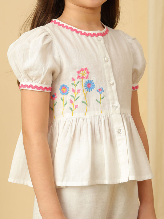 Girls off-white cotton co-ord set with floral embroidered peplum top, puff sleeves and matching wide-leg pants with colorful floral embroidery.